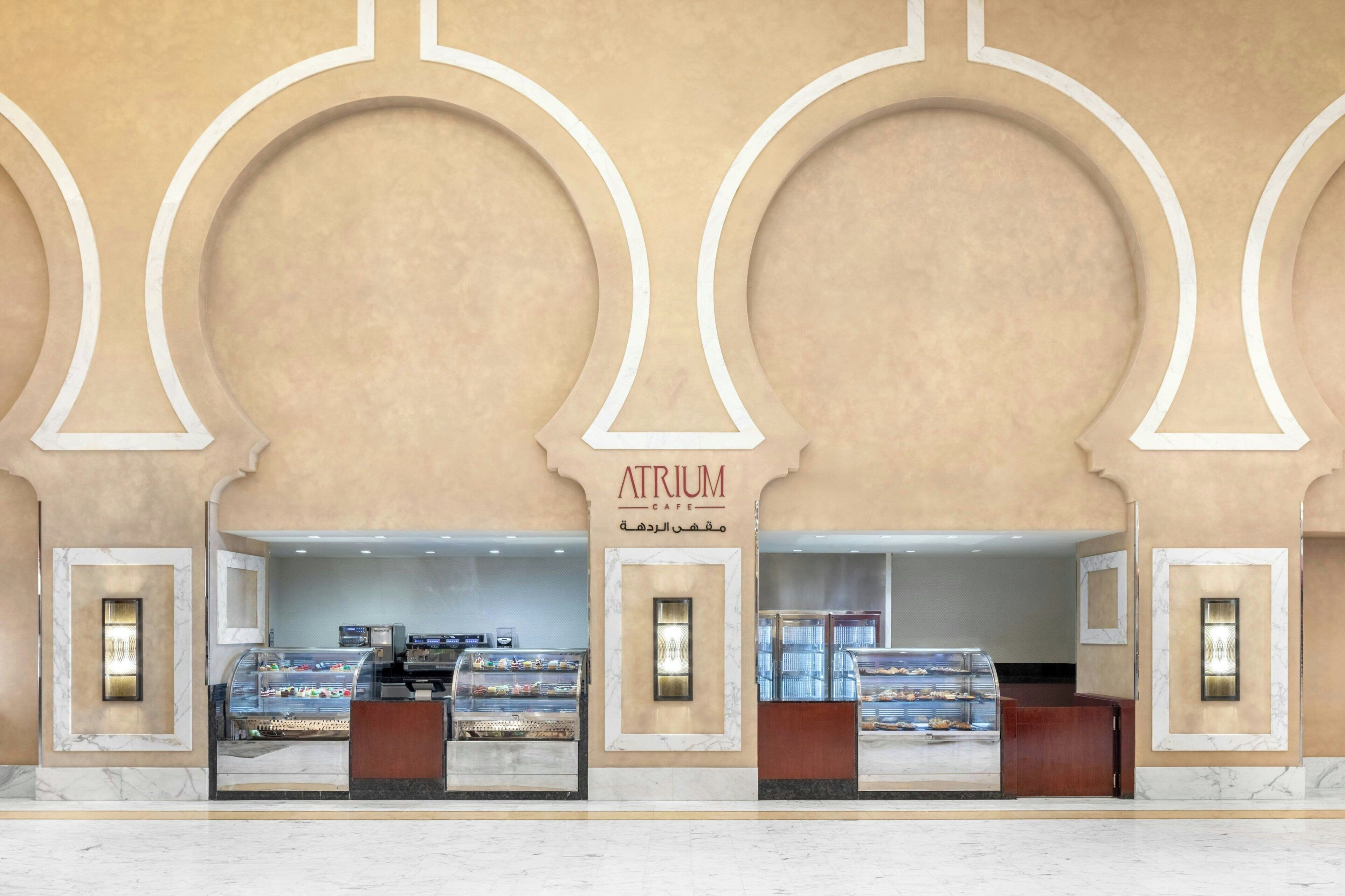 A cafe with a marble counter and display cases of pastries.
