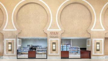 A cafe with a marble counter and display cases of pastries.