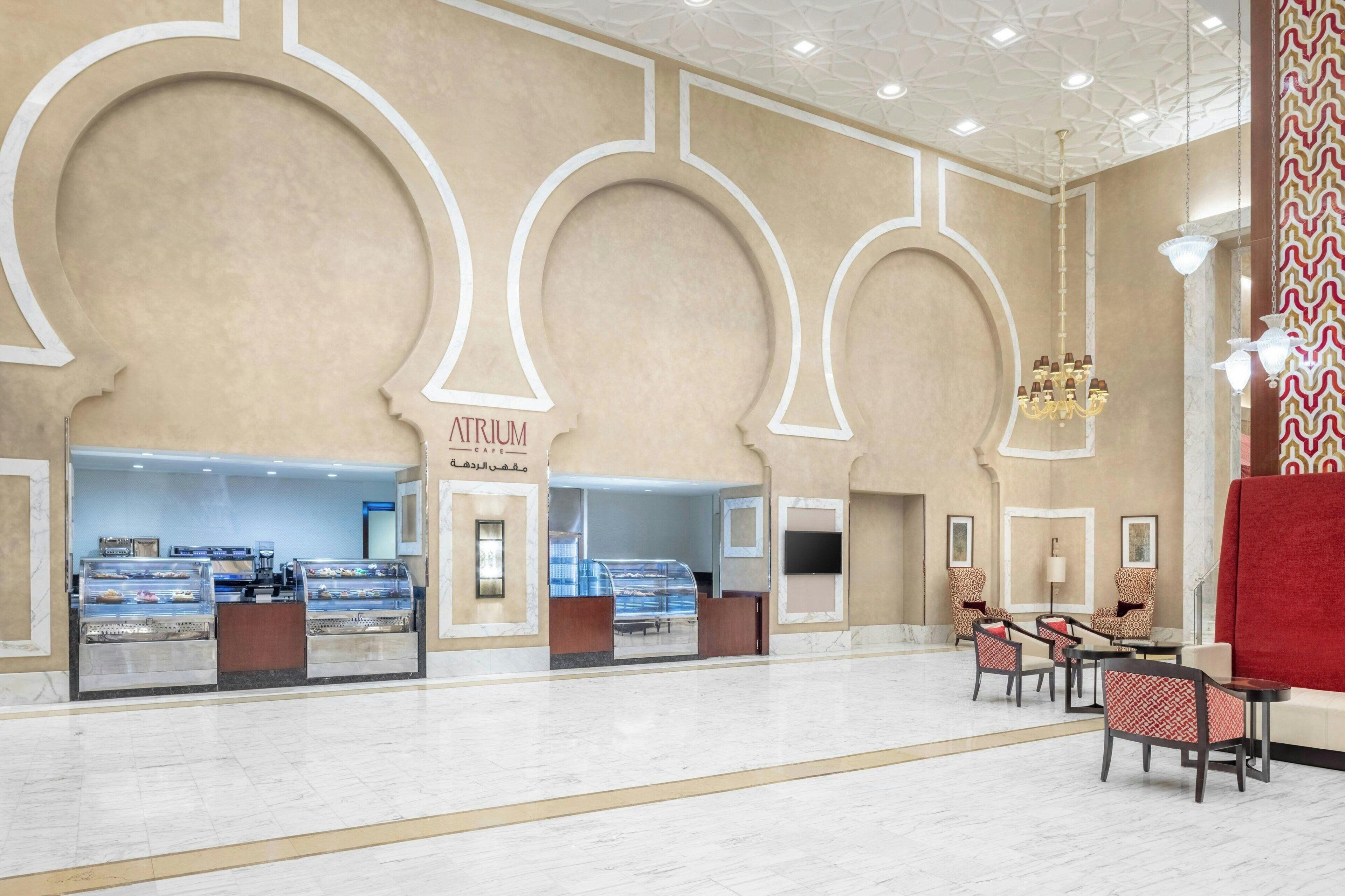 A spacious lobby with a central atrium, seating area, and a food counter.