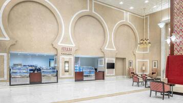 A spacious lobby with a central atrium, seating area, and a food counter.