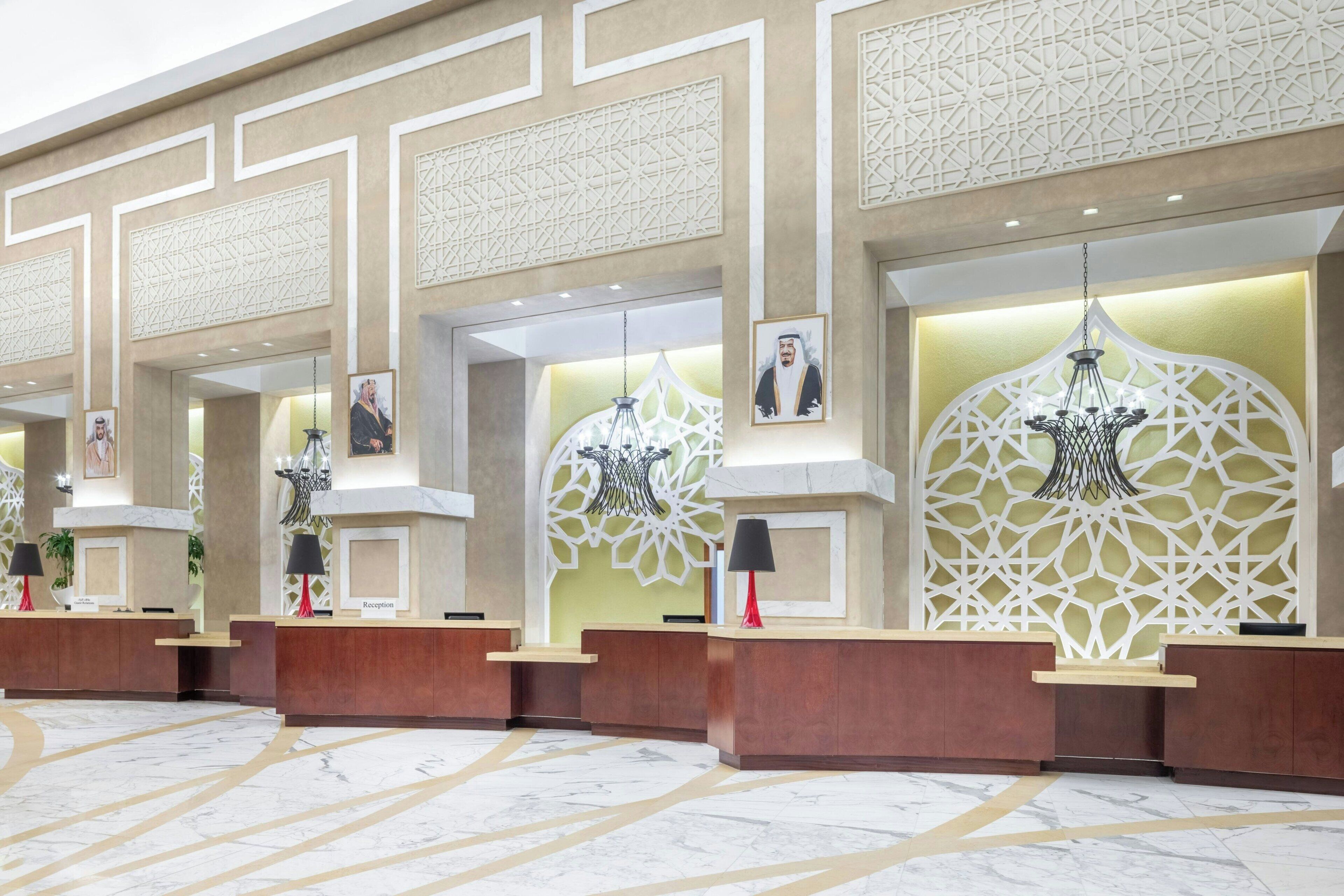 A reception area with three wooden reception desks, each with a nameplate, a black lamp, and framed pictures on the wall.