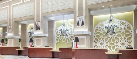 A reception area with three wooden reception desks, each with a nameplate, a black lamp, and framed pictures on the wall.