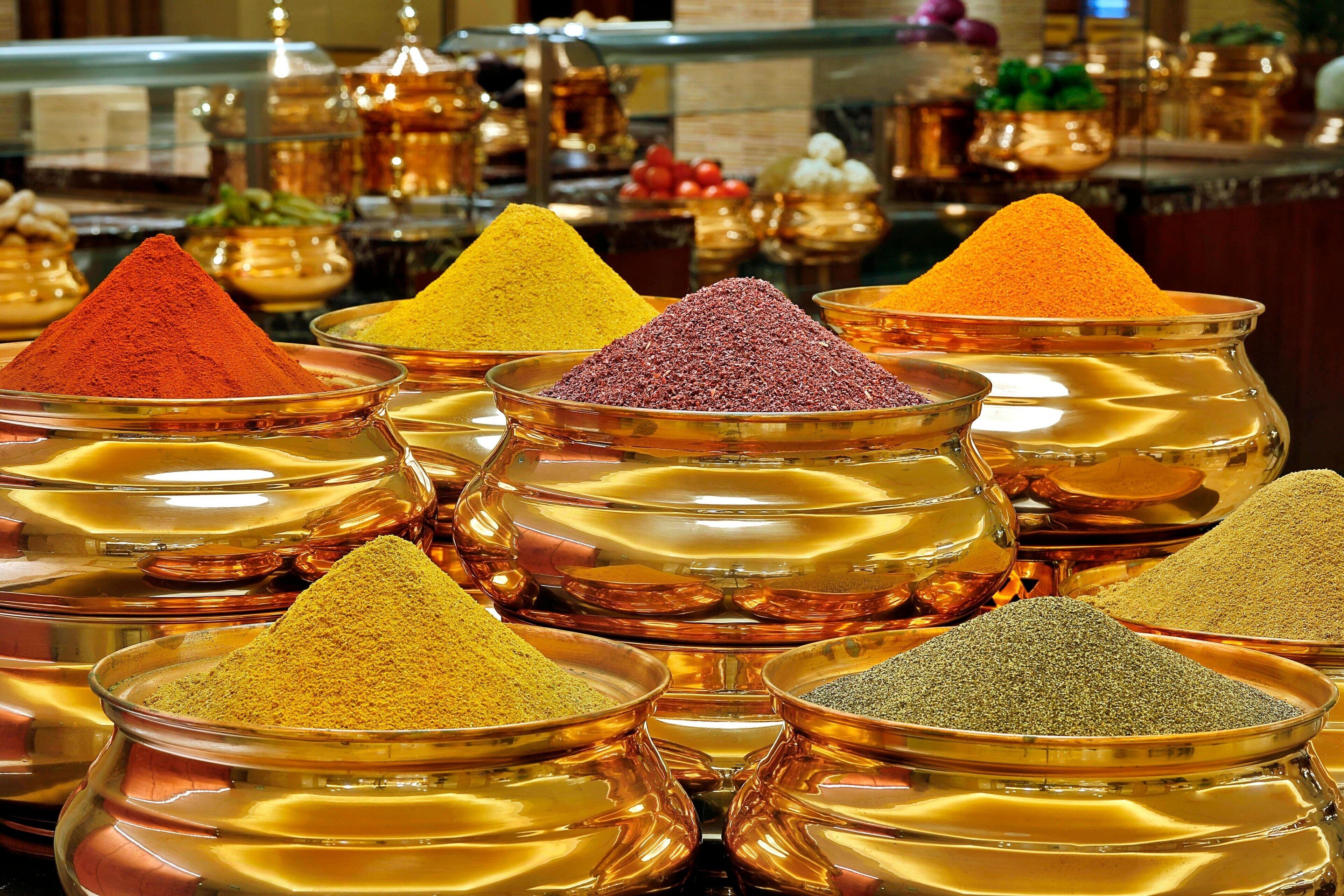 A variety of spices displayed in copper bowls.