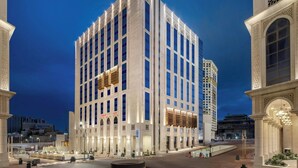 A modern hotel with a central courtyard, multiple floors, and a prominent entrance with decorative elements.