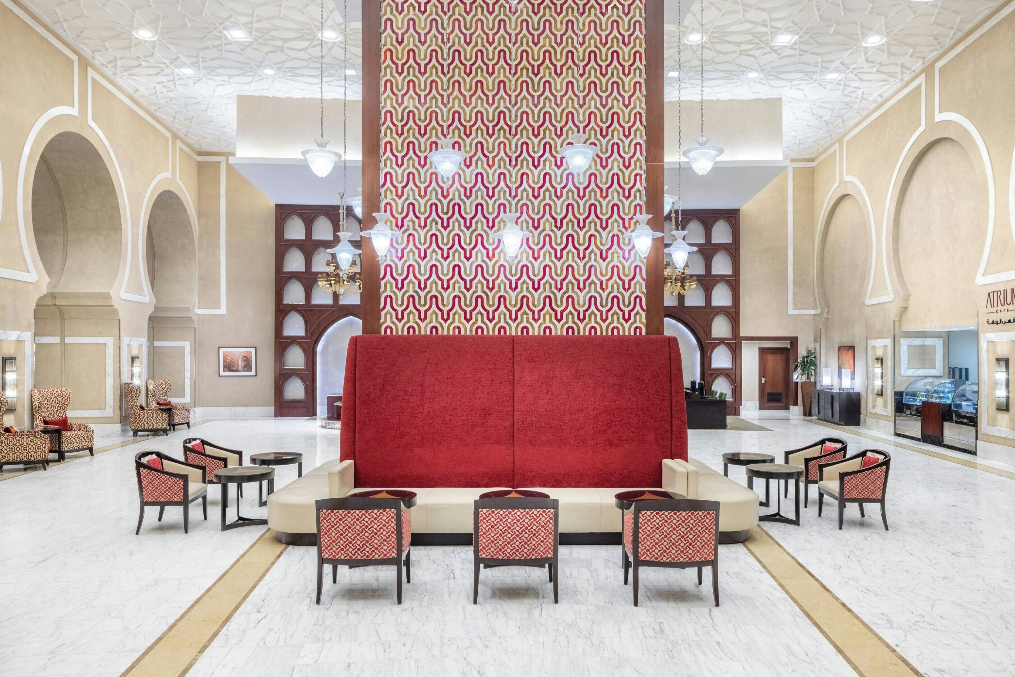 A spacious lobby with a red sofa, patterned chairs, and a decorative wall.