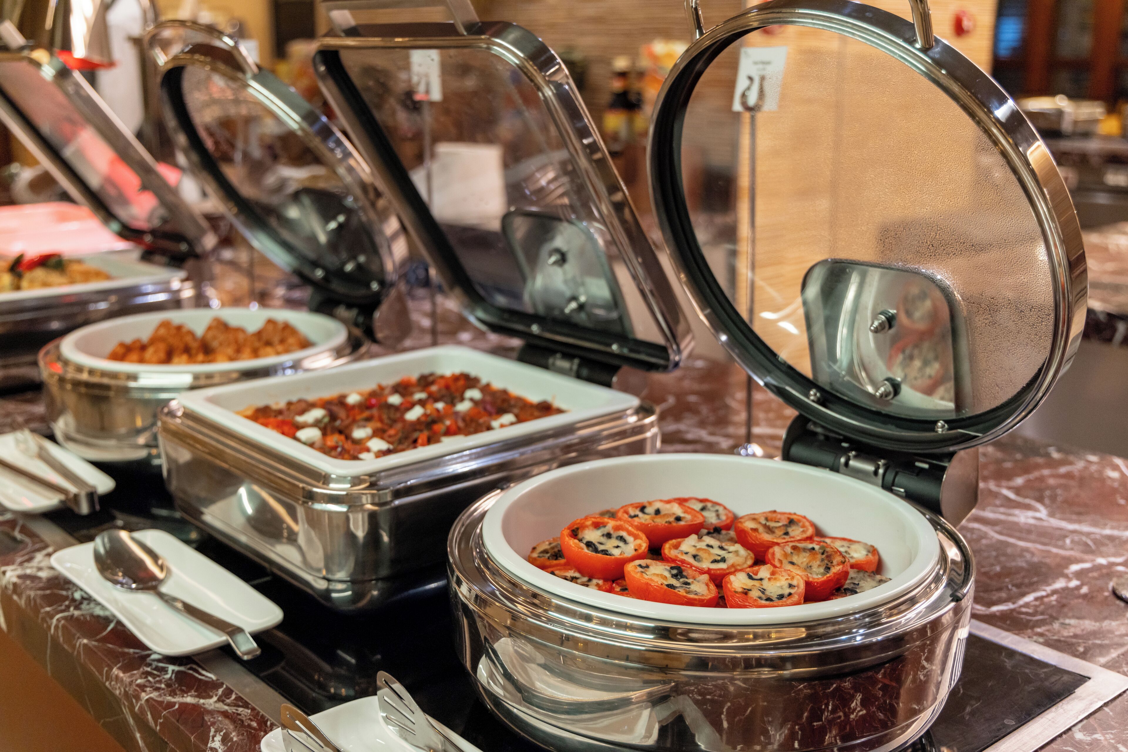 A buffet with various food items in clear containers, including a bowl of stuffed tomatoes.