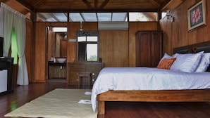 Quarto de madeira com cama, cómoda e televisão.