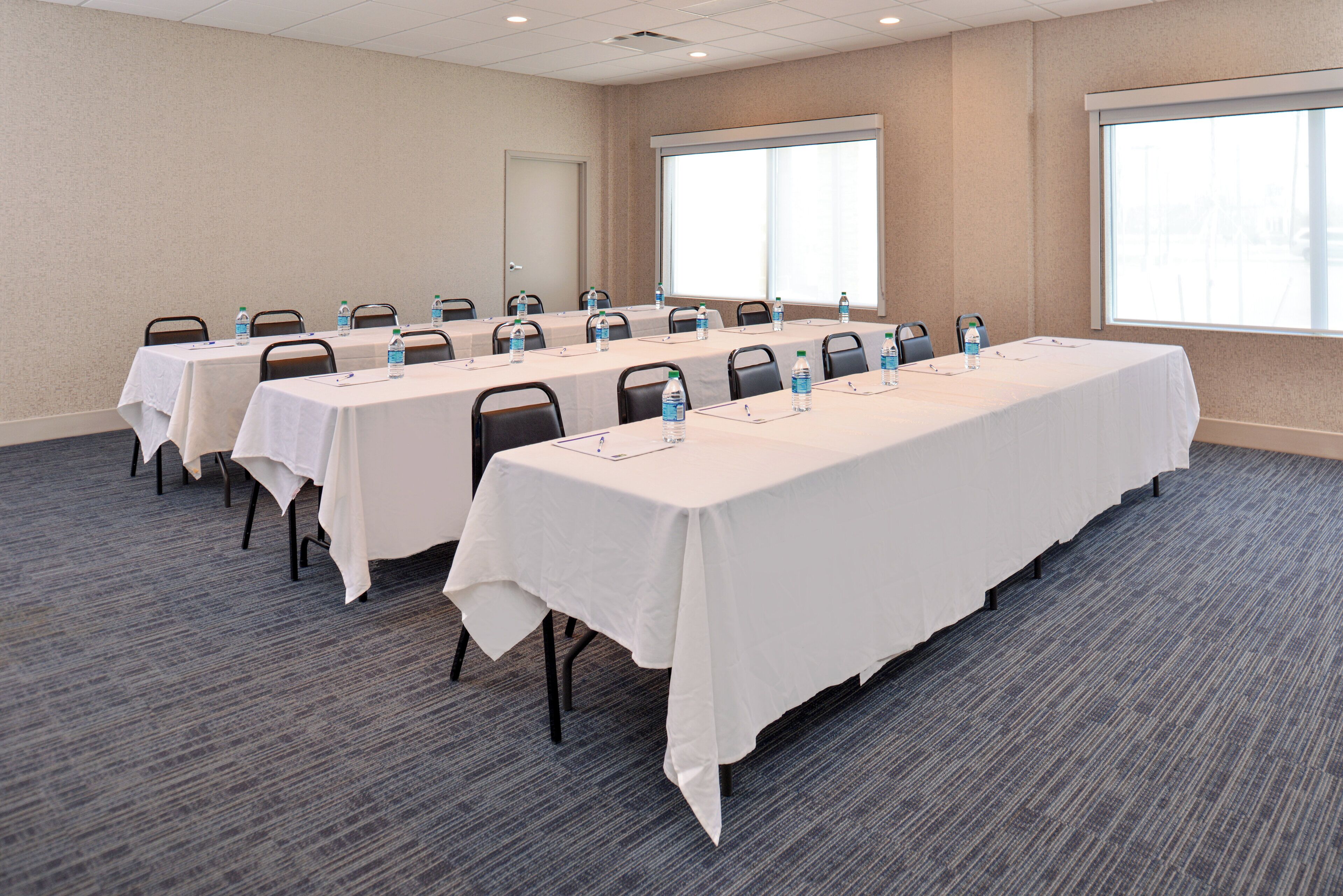 A conference room with multiple tables, each equipped with water bottles and nameplates.