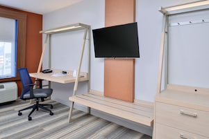 Un espacio de oficina moderno con escritorio, silla y televisor de pantalla plana montado.