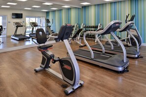Un gimnasio con cintas de correr, elípticas y mancuernas.