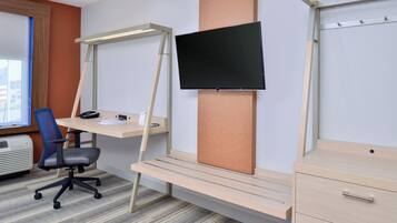A modern office space with a desk, chair, and mounted TV.