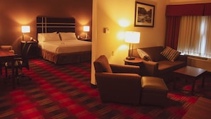 A hotel room with a bed, a sofa, a chair, a table, and a lamp. - Holiday Inn Express & Suites Cumberland - La Vale by IHG (Cumberland)