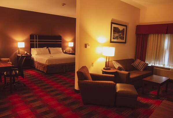 A hotel room with a bed, a sofa, a chair, a table, and a lamp. - Holiday Inn Express & Suites Cumberland - La Vale by IHG (Cumberland)