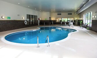 Piscina interna com elevador de piscina, área de estar e vista para o exterior.