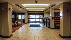 A hotel lobby with a reception desk, a vending machine, and a seating area with chairs. - Holiday Inn Express & Suites Cumberland - La Vale by IHG (Cumberland)