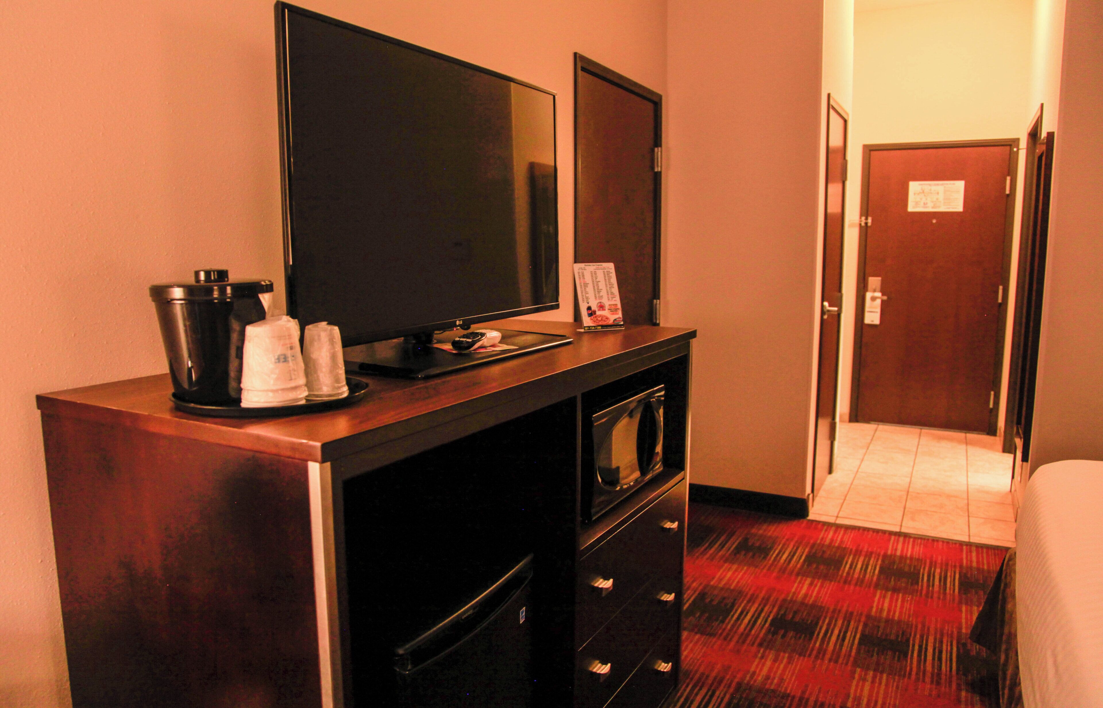 Ein Hotelzimmer mit Flachbildfernseher, Kaffeemaschine, Mikrowelle und einer Tür zu einem weiteren Zimmer.