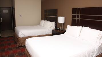 Habitación de hotel con dos camas, una mesita de noche, una lámpara y una puerta.