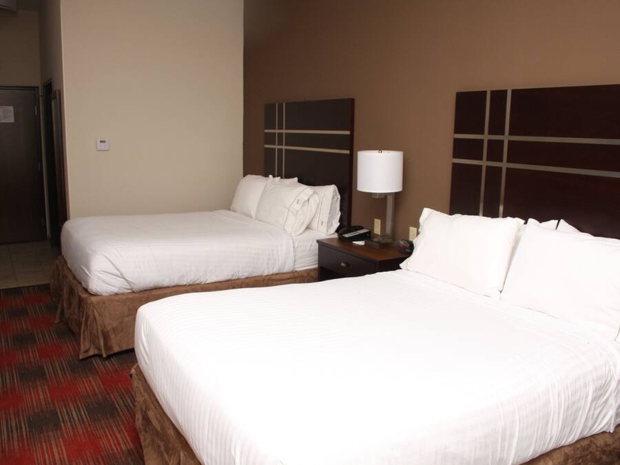 Habitación de hotel con dos camas, una mesita de noche, una lámpara y una puerta.