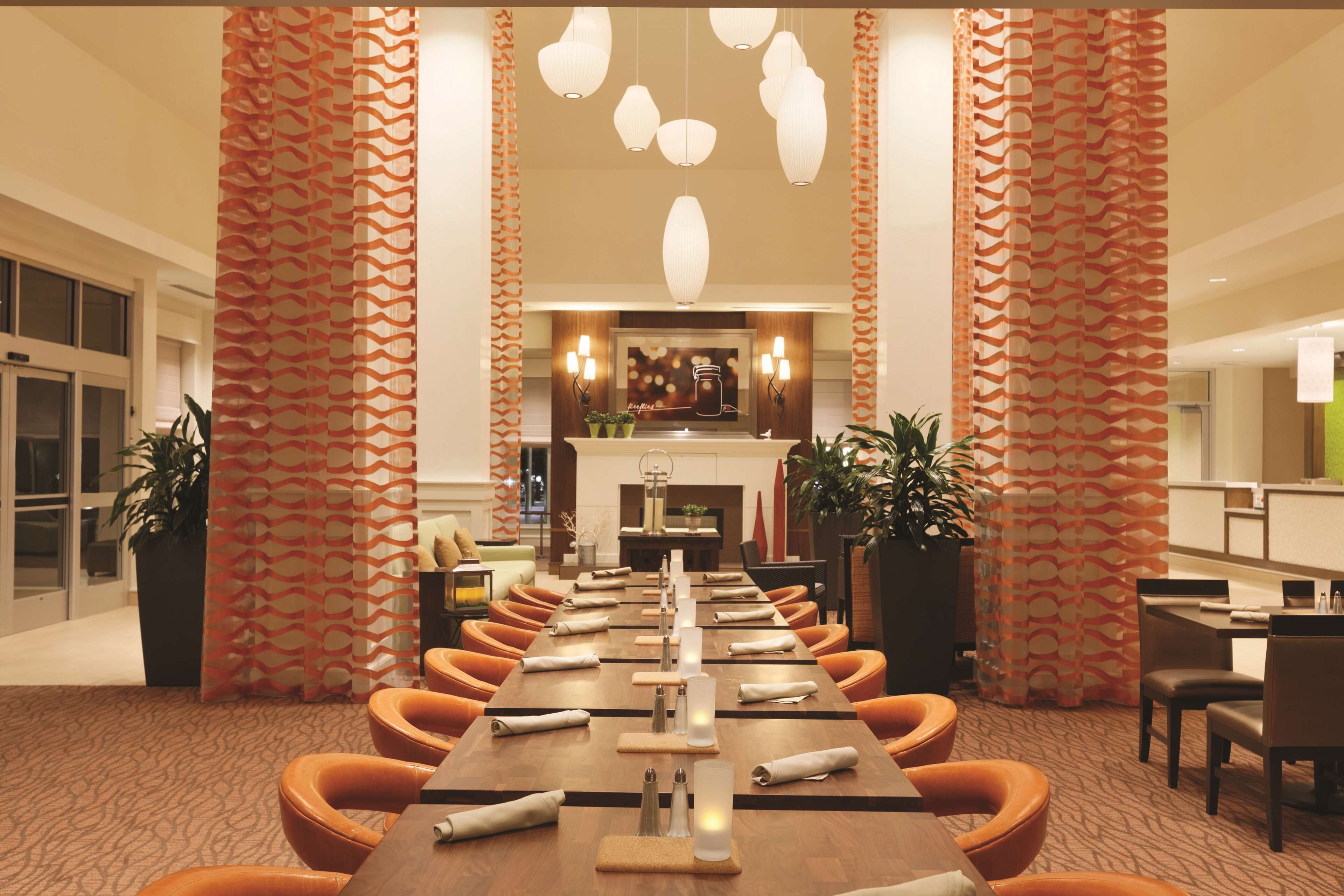 A conference room with a long table, orange chairs, and pendant lighting.