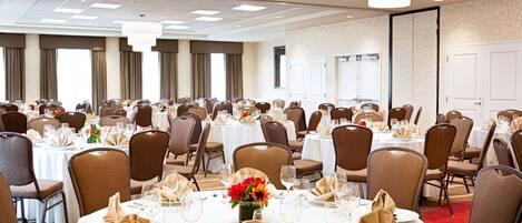 A banquet hall with round tables set for dining, arranged in rows with chairs.