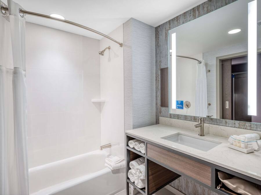 A modern bathroom with a bathtub, a shower, a vanity with a sink, and a large mirror.
