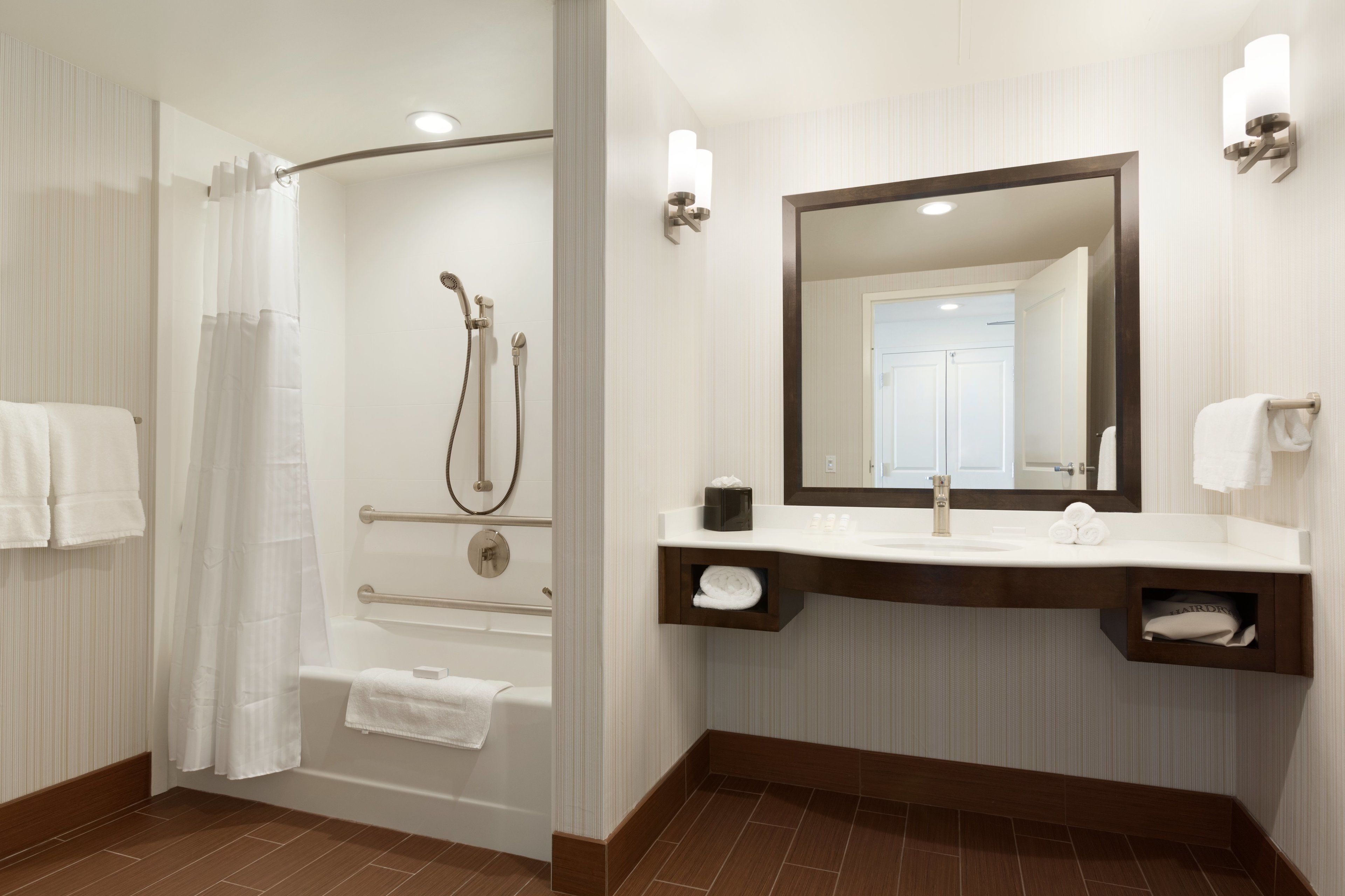 A modern bathroom with a shower, bathtub, vanity, and a large mirror.