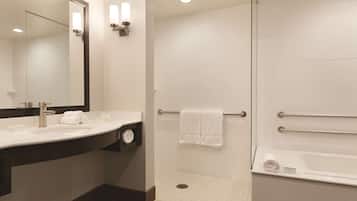Ein modernes Badezimmer mit großem Spiegel, Waschbecken mit Handtuchhalter, Dusche inklusive Haltegriff und Badewanne.