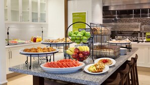 A buffet setup with various food items including fruits, vegetables, and pastries. - Hilton Garden Inn Boston Logan Airport (Boston)