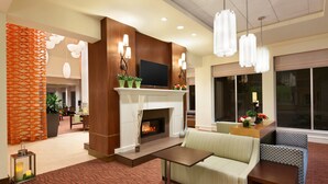 A modern lobby with a fireplace, seating area, and decorative lighting. - Hilton Garden Inn Boston Logan Airport (Boston)