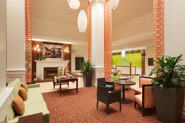 Un moderno vestíbulo de hotel con chimenea, zona de estar y columnas decorativas.