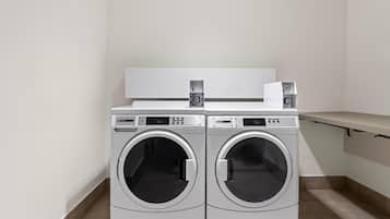 A laundry room with two front-loading washing machines and a dryer.