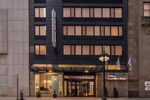 A modern building with a black facade and multiple windows. There is a sign for Hilton Garden Inn and a flagpole with flags. - Hilton Garden Inn Chicago Downtown Riverwalk (Chicago)
