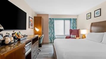 Ett hotellrum med en säng, ett skrivbord, en stol och en tv.