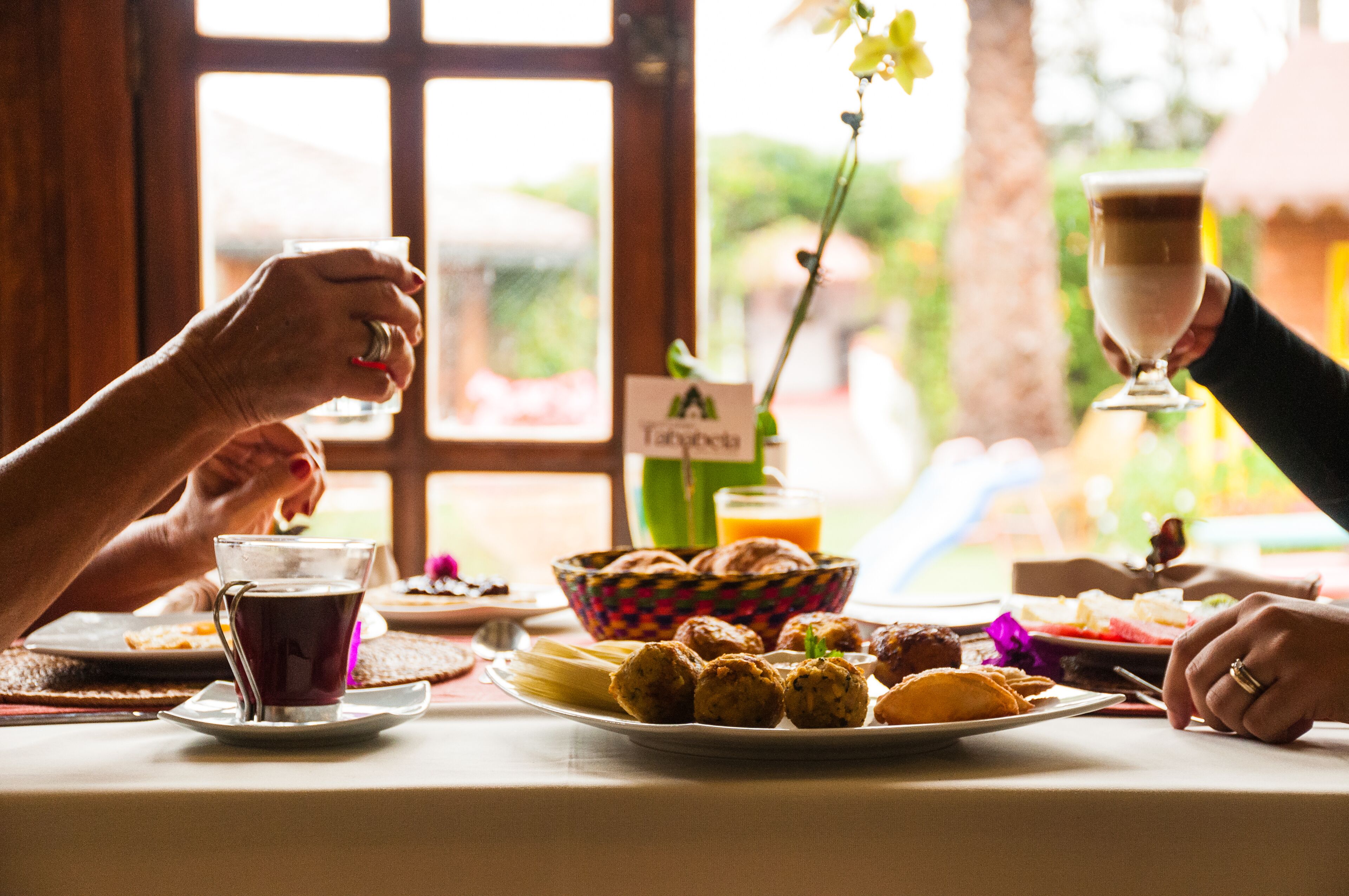 A breakfast table with a variety of foods, including bread, pastries, and a drink.