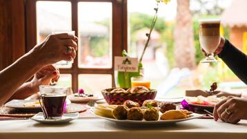 A breakfast table with a variety of foods, including bread, pastries, and a drink.