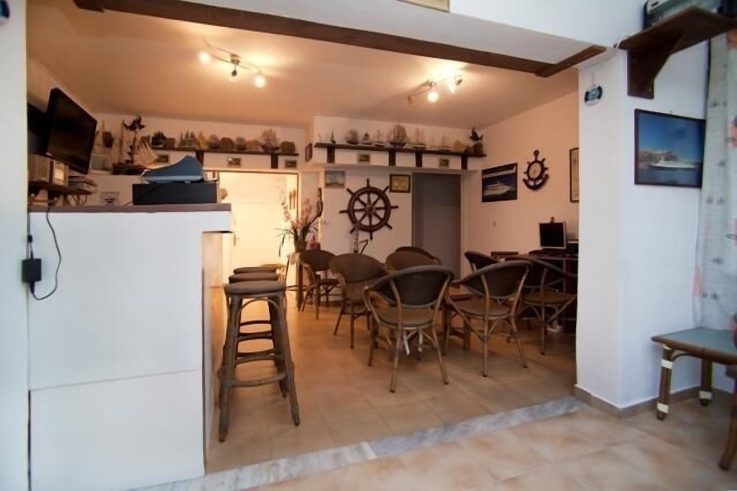A dining area with wooden chairs and a central table, a television on a stand, and nautical-themed decor.