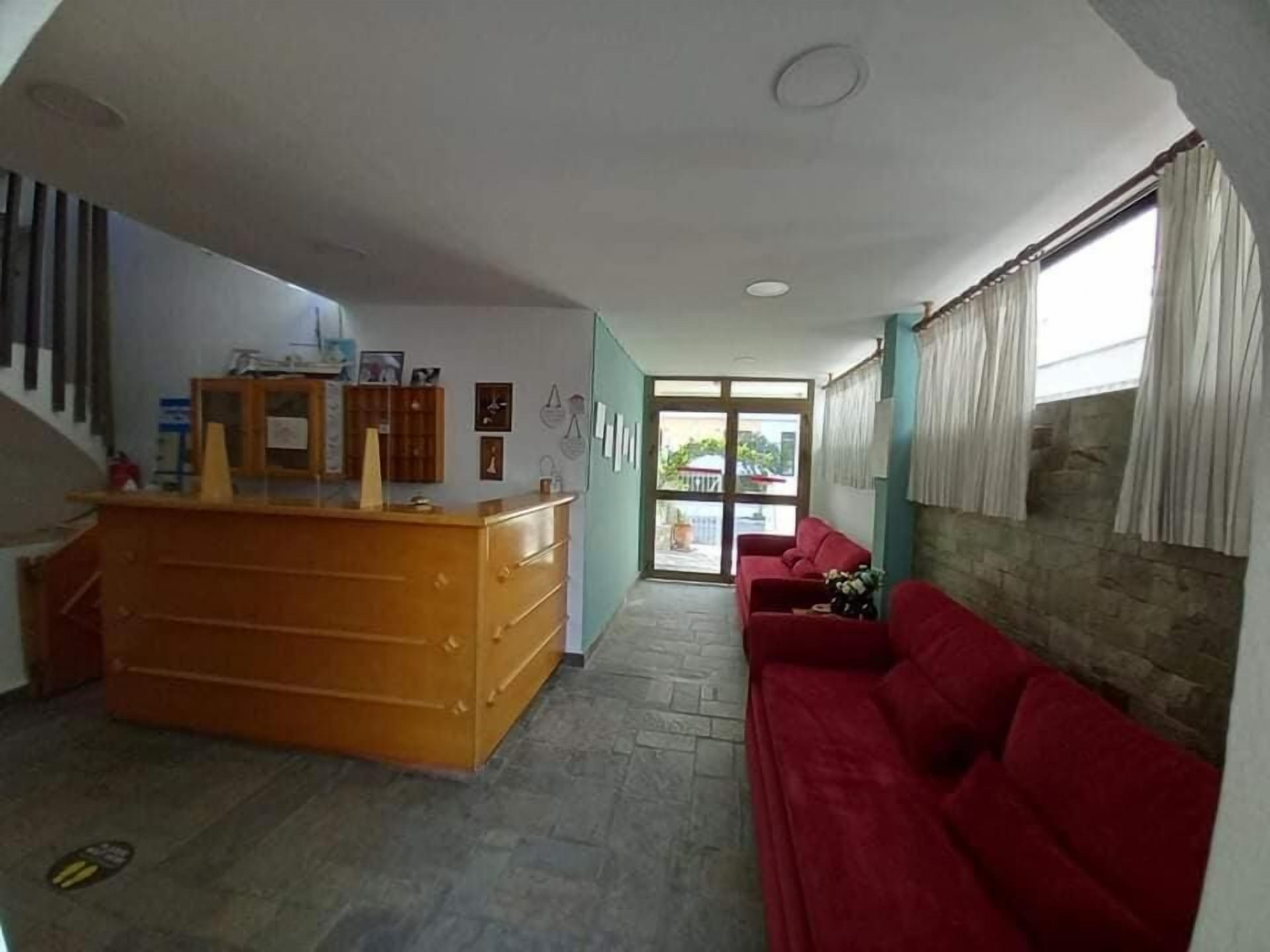 Ein Empfangsbereich mit einem Holzbüro, einem roten Sofa und einer Steinwand.