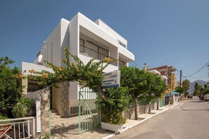 A modern two-story building with a sign advertising apartments and studios. - Kardamena Holiday Apartments (Kos)