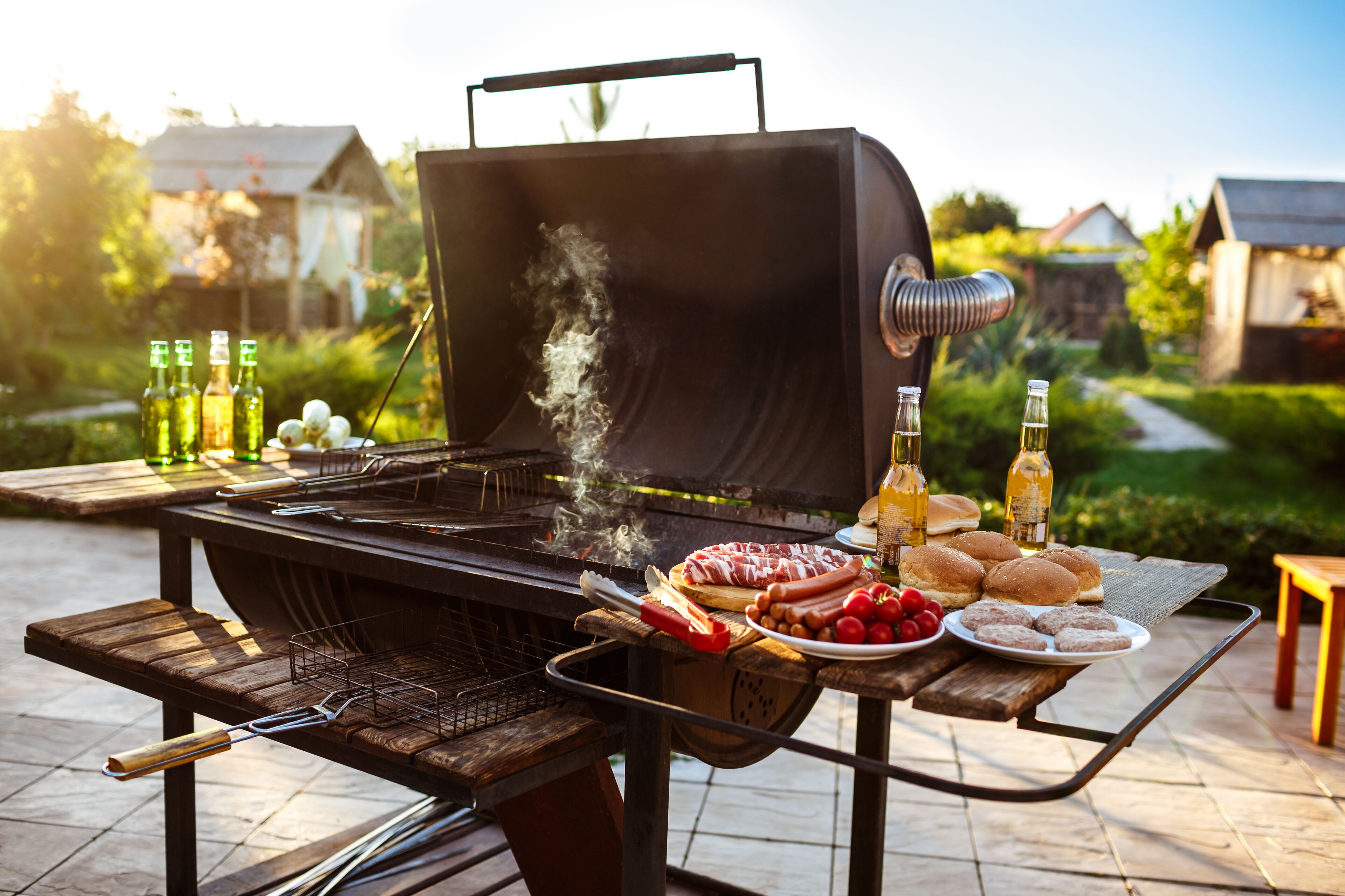 Un barbecue avec de la nourriture et des boissons, le tout disposé sur une table en bois, dans un cadre extérieur.