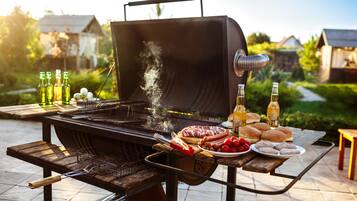Un barbecue avec de la nourriture et des boissons, le tout disposé sur une table en bois, dans un cadre extérieur.