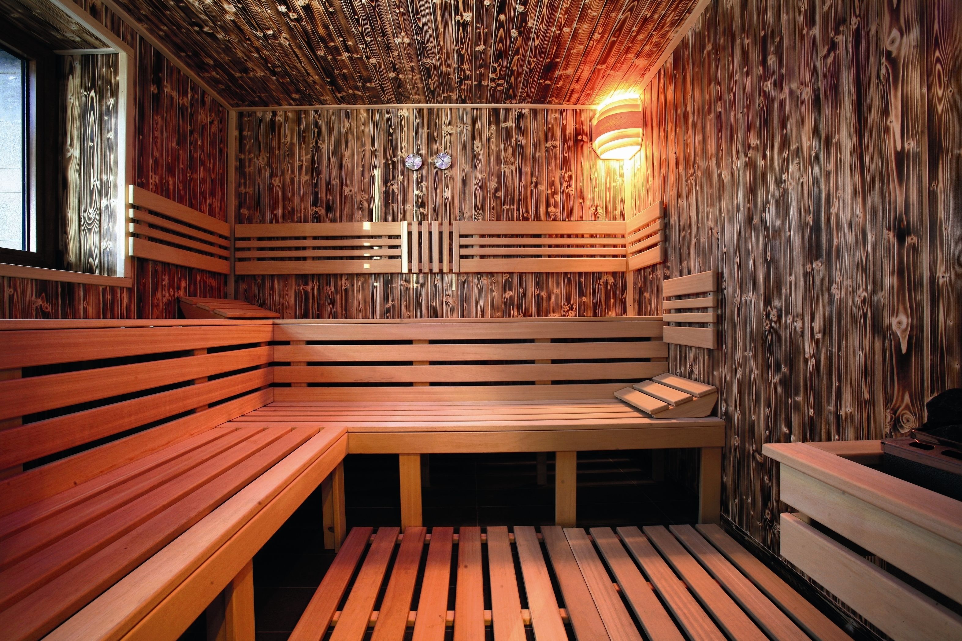Eine Sauna mit Holzbänken und einer horizontalen Wandgestaltung.