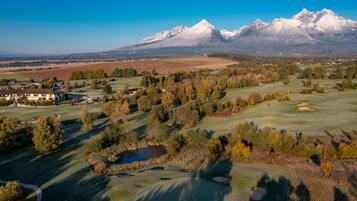 Un parcours de golf offrant une vue sur des montagnes enneigées en arrière-plan.