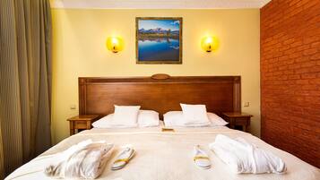 A hotel room with a bed, two nightstands, a painting on the wall, and a brick wall.