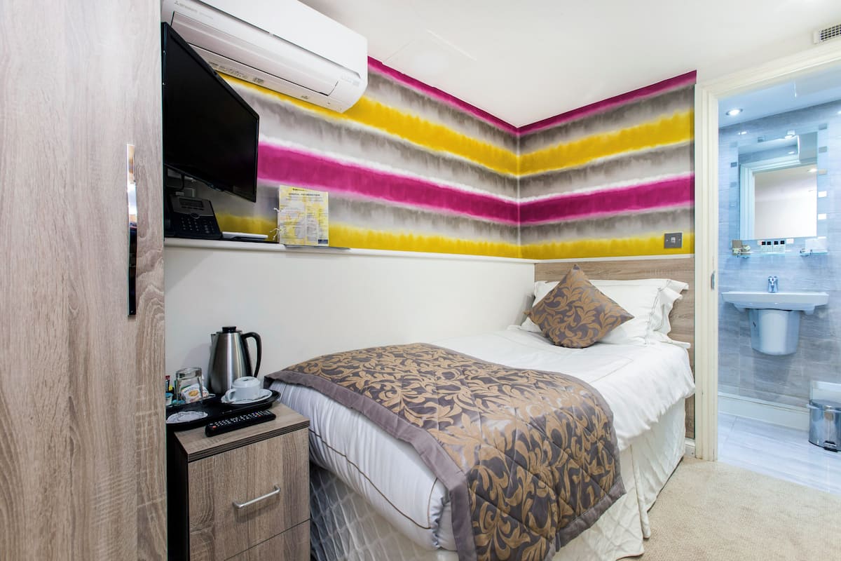 A hotel room with a bed, bedside table, and a bathroom with a sink.