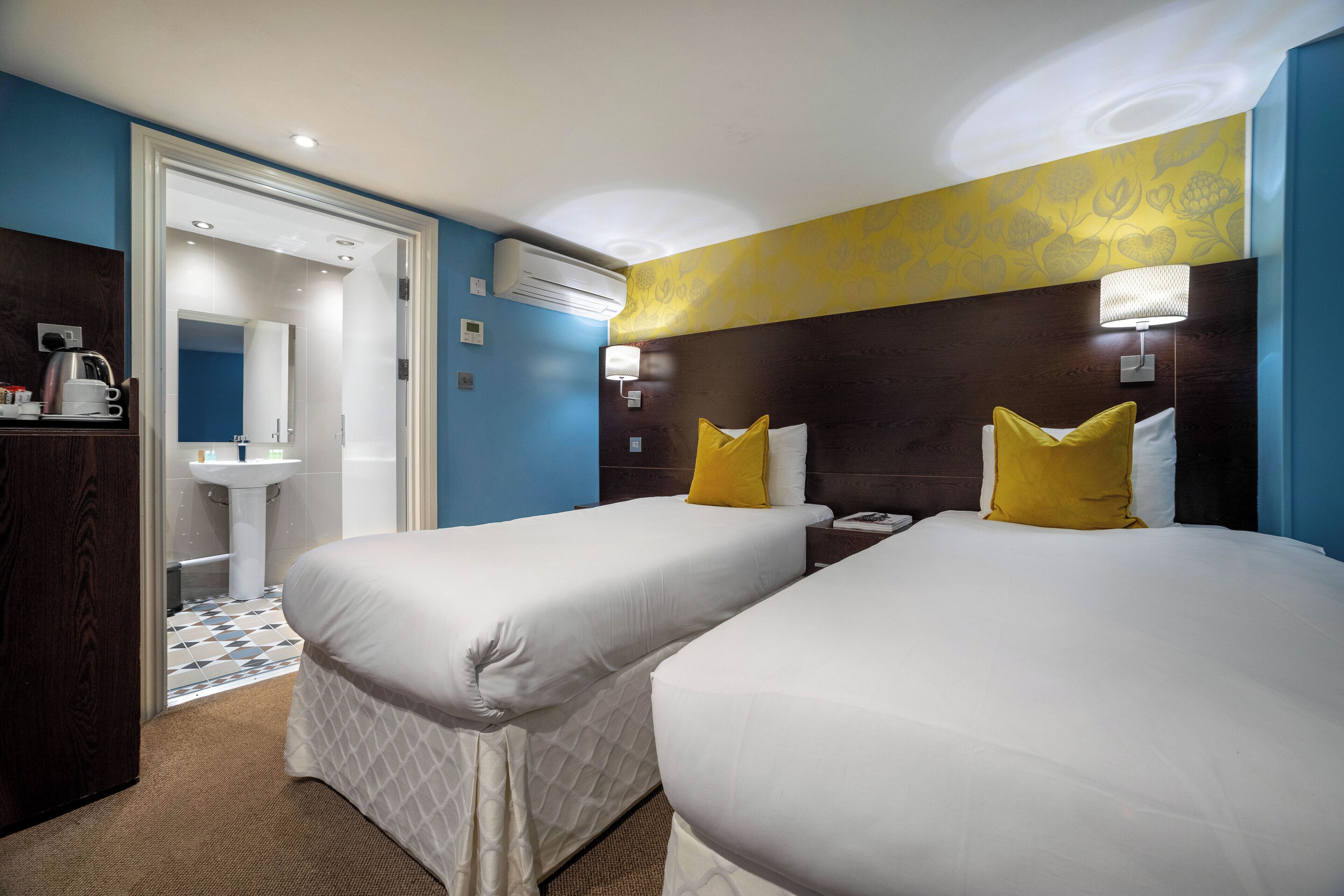 Een hotelkamer met twee bedden, een badkamer en een minibar.