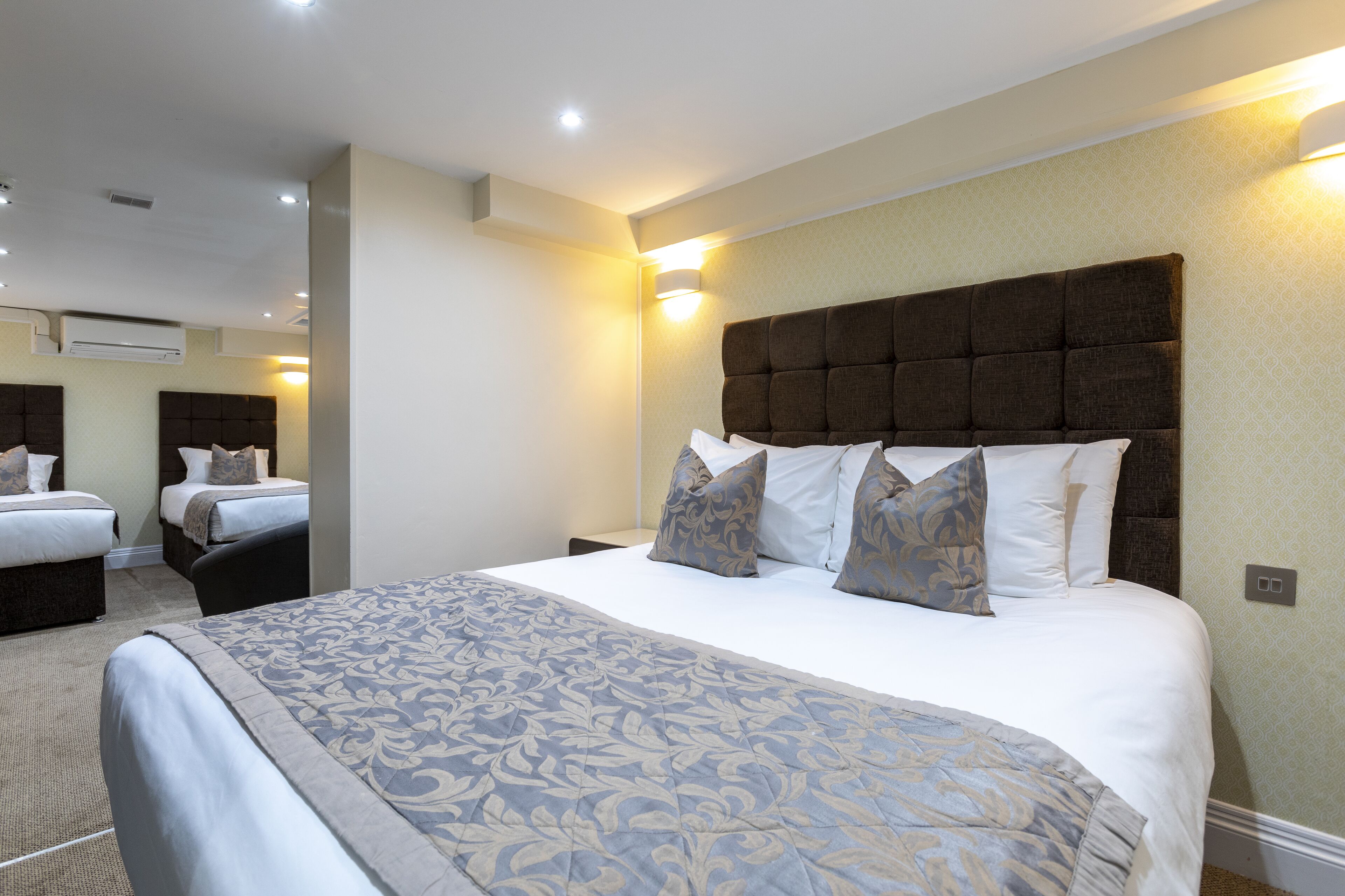 A hotel room with a large bed, two smaller beds, and a seating area.