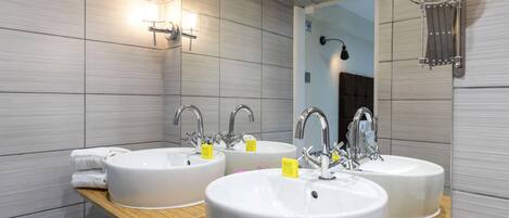 A modern bathroom with three sinks, a wooden vanity, and a large mirror.