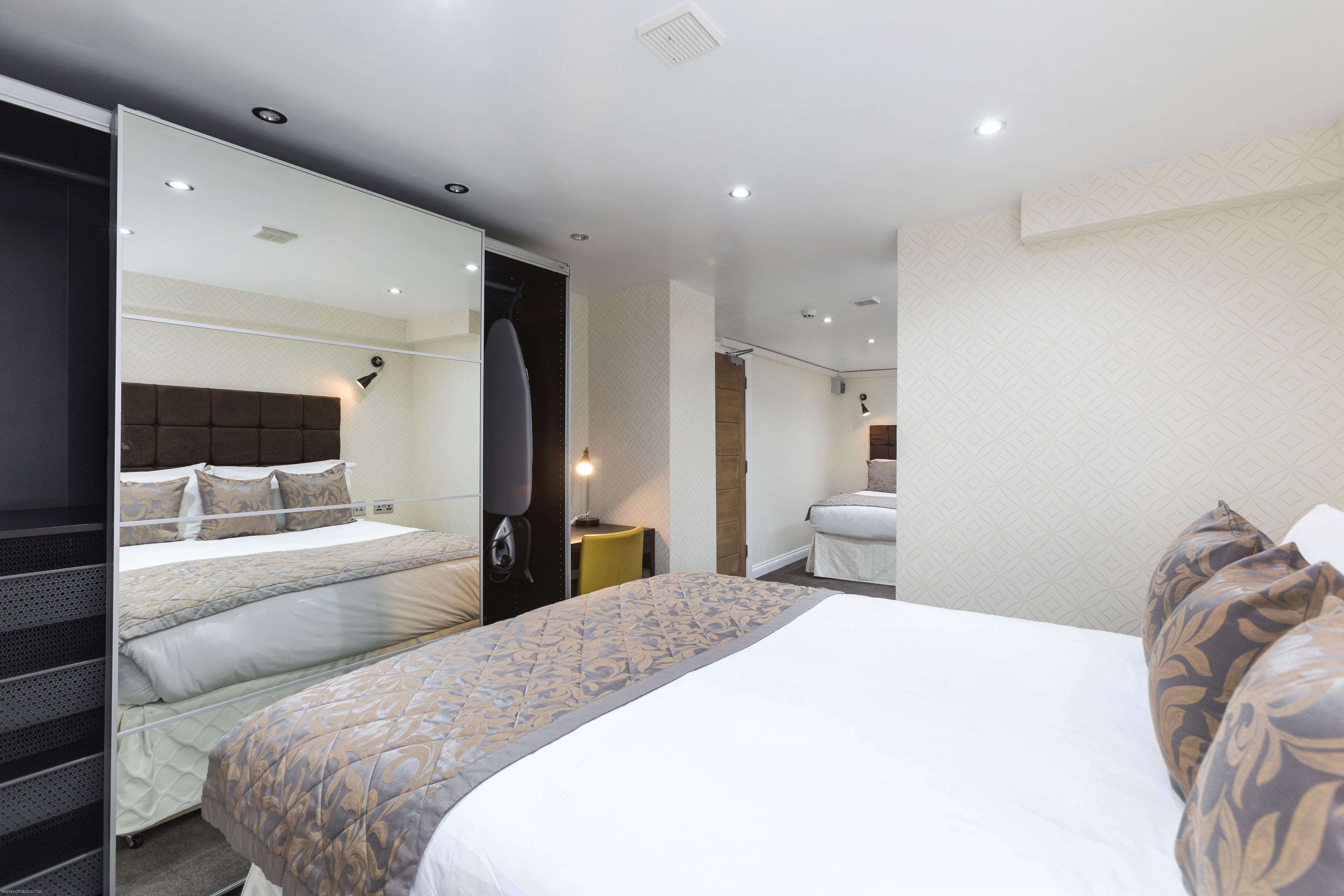 A hotel room with a bed, a mirror, a desk, and a chair.