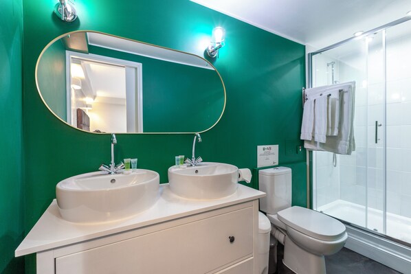 Une salle de bain avec deux lavabos, des toilettes et une douche.
