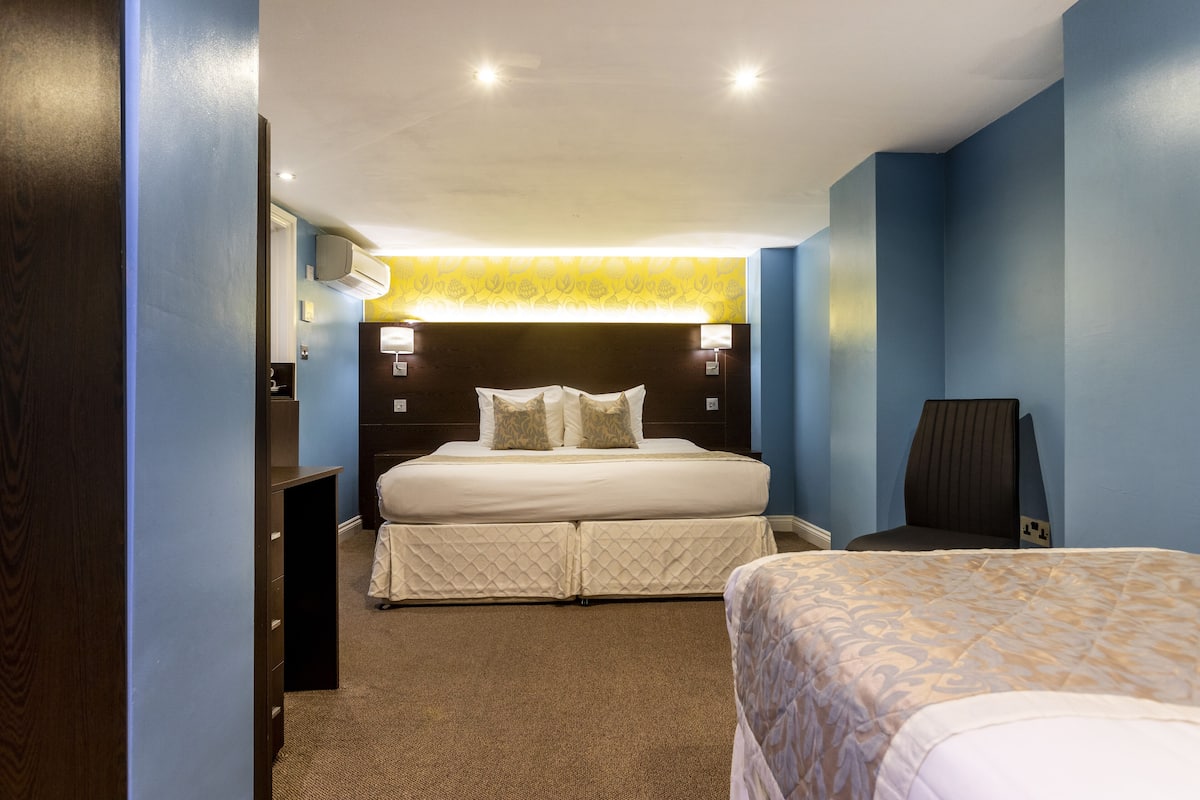 A hotel room with a large bed, a desk, and a chair.